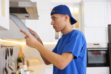 Professional janitor removing filter from kitchen hood indoors