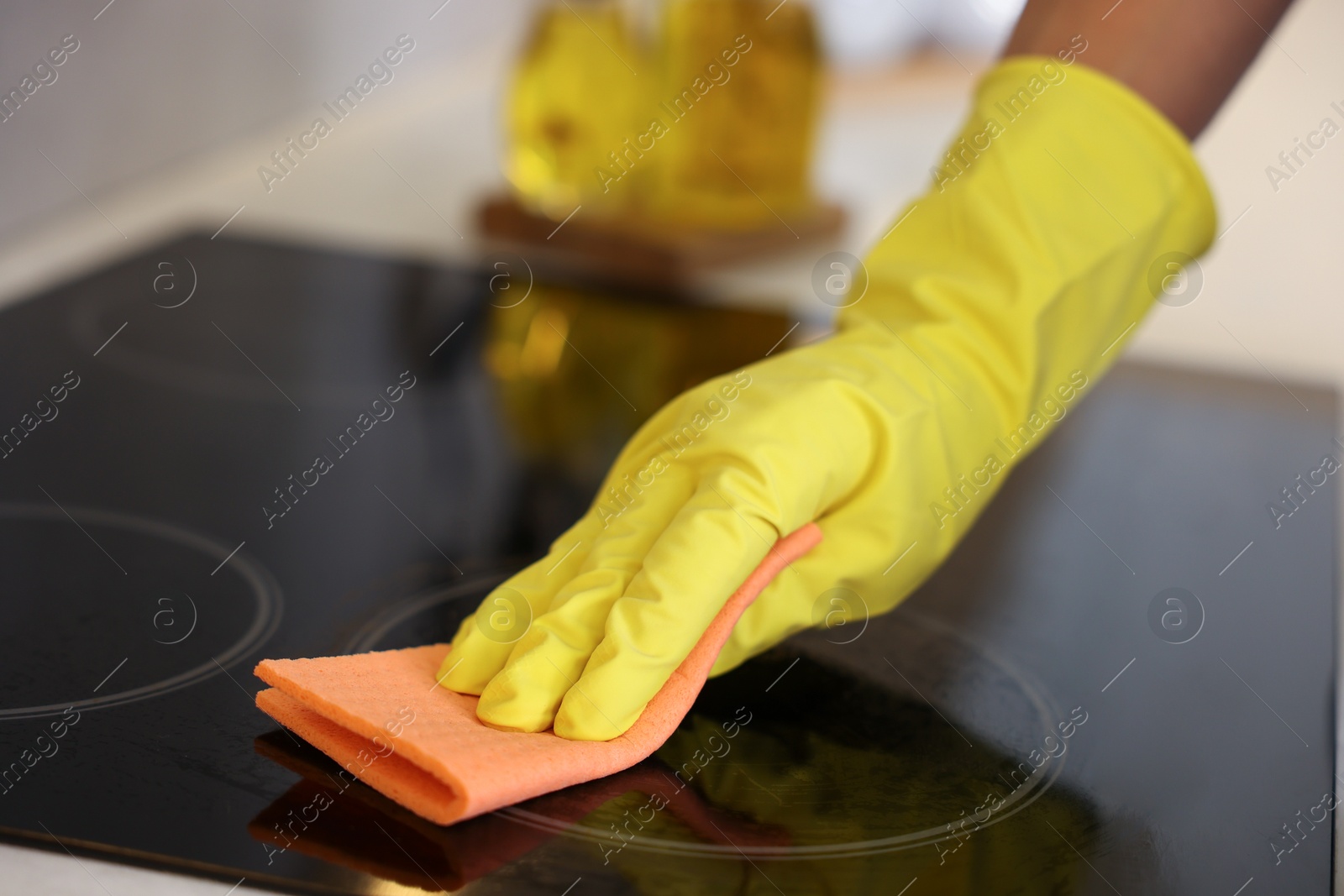 Photo of Man cleaning electric stove with rag in kitchen, closeup