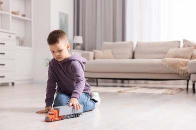 Photo of Little boy playing with toy car at home. Space for text