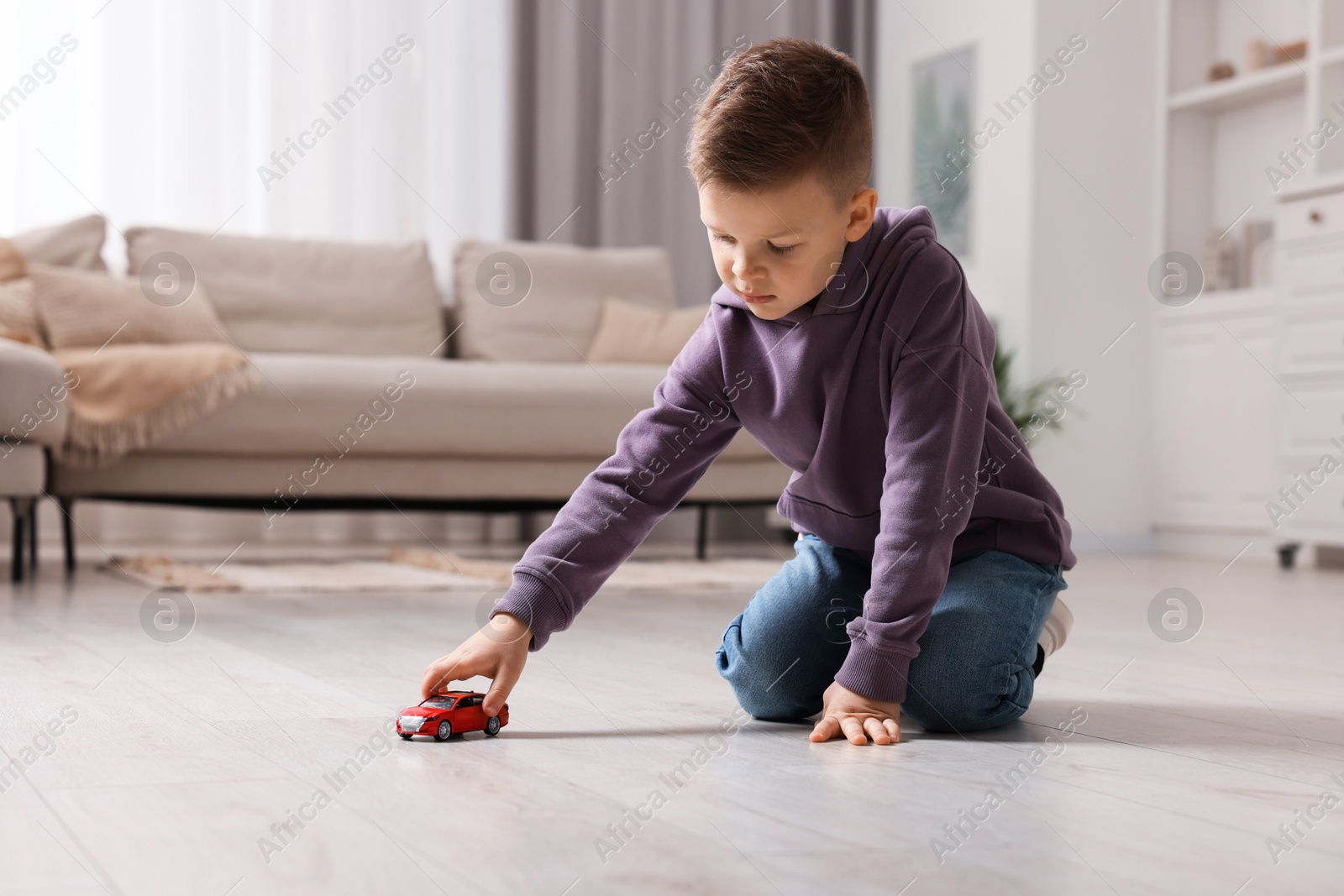 Photo of Little boy playing with toy car at home