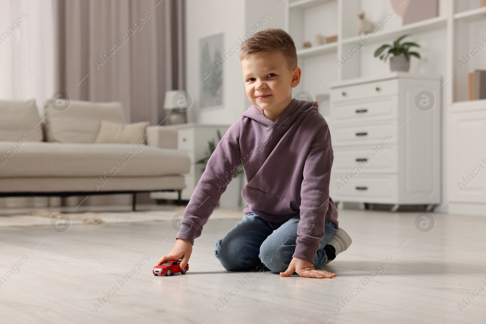 Photo of Little boy playing with toy car at home