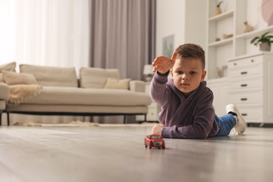 Little boy playing with toy car at home. Space for text