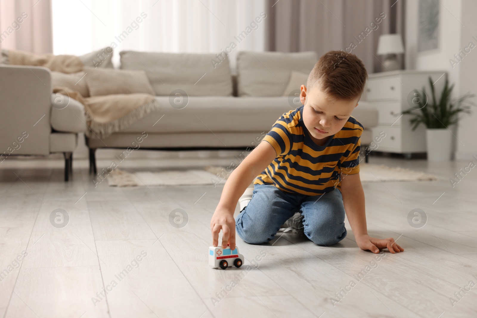 Photo of Little boy playing with toy car at home. Space for text