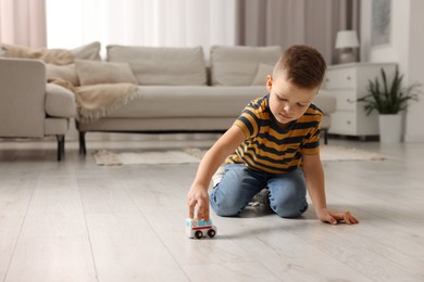 Little boy playing with toy car at home. Space for text