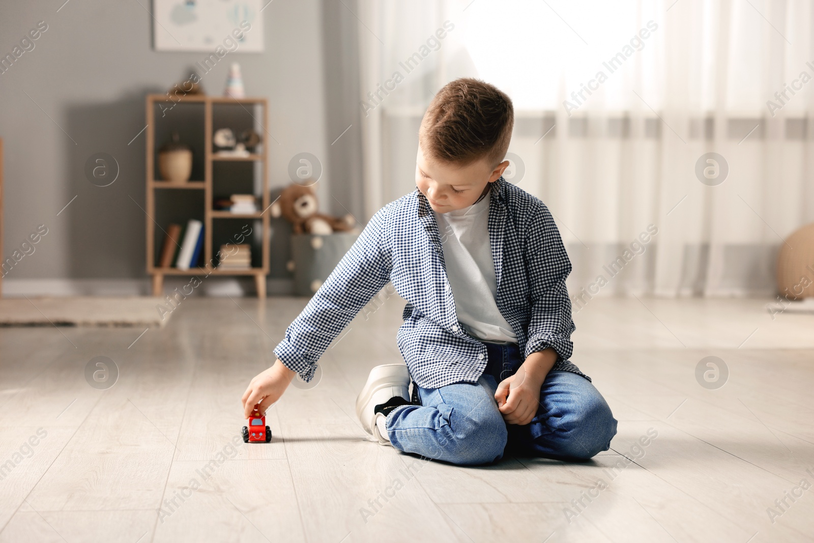 Photo of Little boy playing with toy car at home