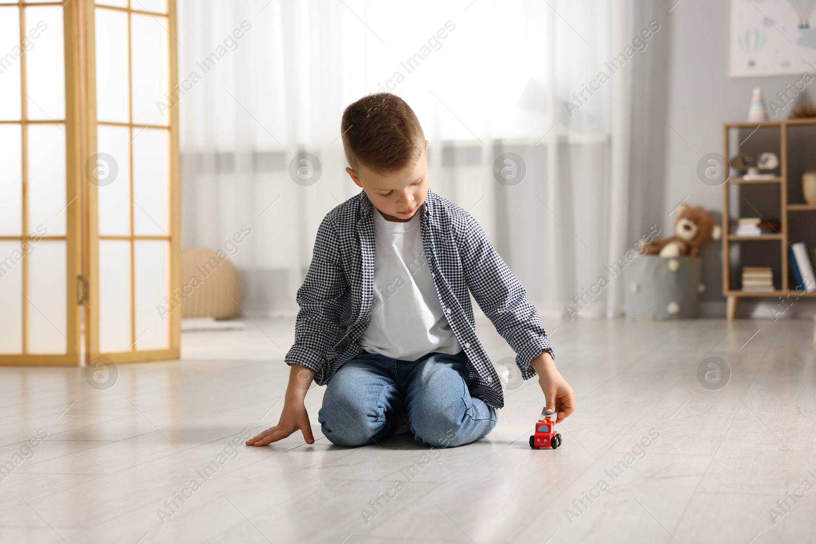 Photo of Little boy playing with toy car at home