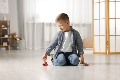 Photo of Little boy playing with toy car at home