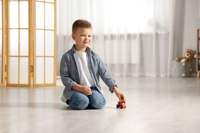 Photo of Little boy playing with toy car at home. Space for text