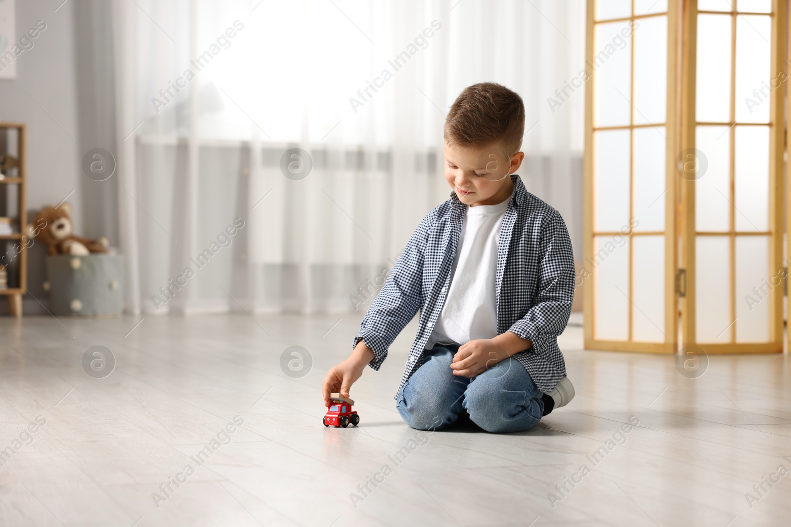 Photo of Little boy playing with toy car at home. Space for text