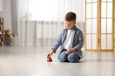 Photo of Little boy playing with toy car at home. Space for text