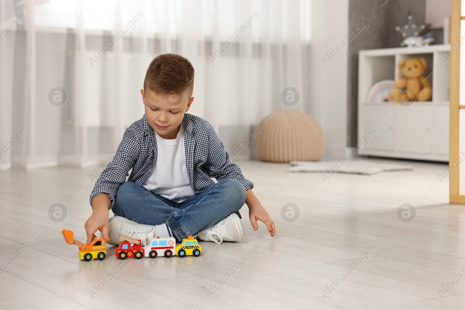 Photo of Little boy playing with toy cars at home. Space for text