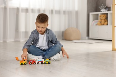 Little boy playing with toy cars at home. Space for text