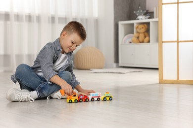 Photo of Little boy playing with toy cars at home. Space for text