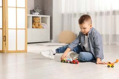 Photo of Little boy playing with toy cars at home. Space for text