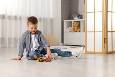 Photo of Little boy playing with toy cars at home. Space for text