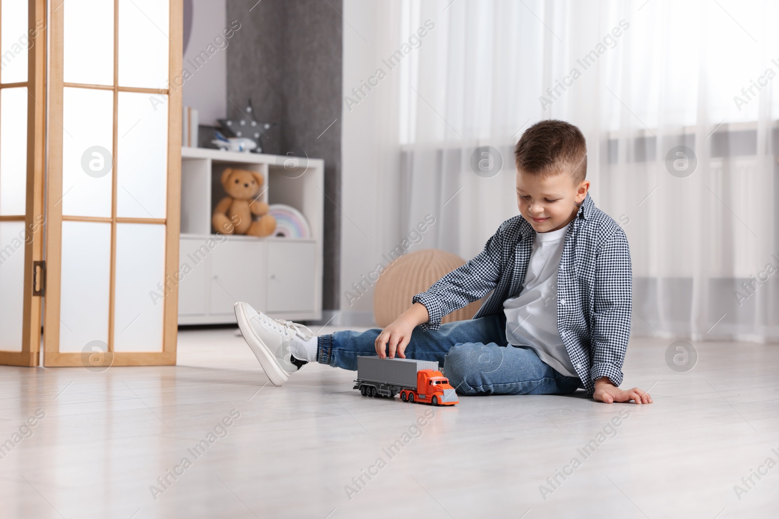 Photo of Little boy playing with toy car at home