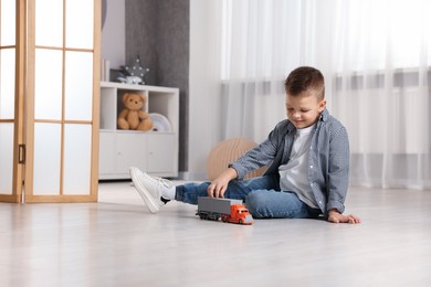 Photo of Little boy playing with toy car at home