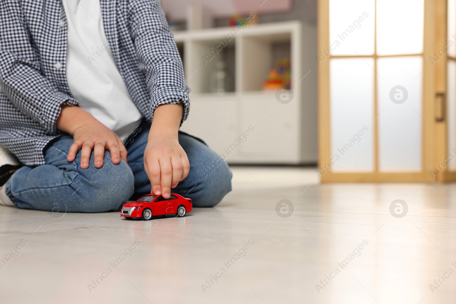 Photo of Little boy playing with toy car at home, closeup. Space for text