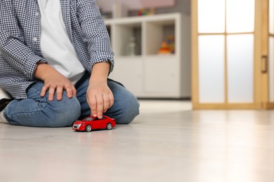 Little boy playing with toy car at home, closeup. Space for text