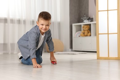 Little boy playing with toy car at home. Space for text