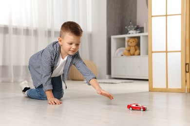 Photo of Little boy playing with toy car at home. Space for text