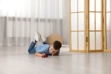 Little boy playing with toy car at home