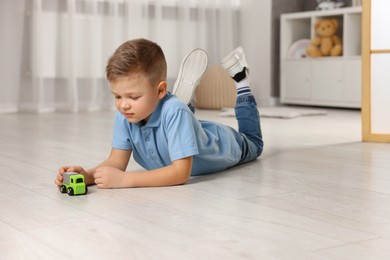 Photo of Little boy playing with toy car at home