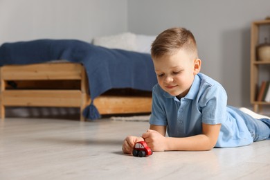 Photo of Little boy playing with toy car at home. Space for text