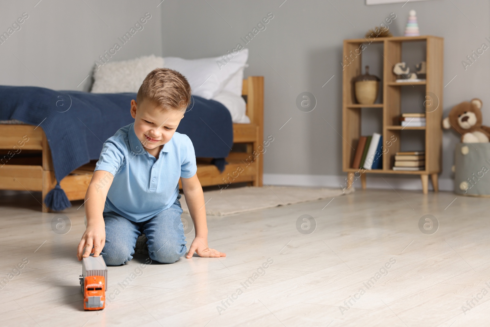 Photo of Little boy playing with toy car at home. Space for text