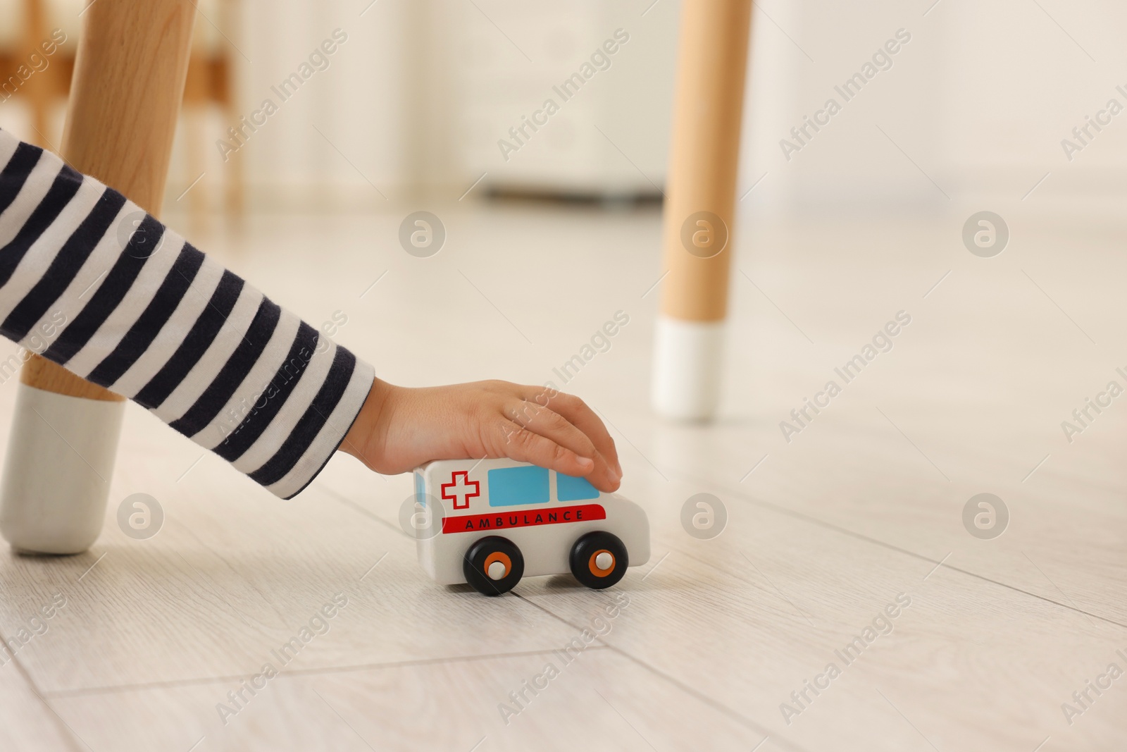 Photo of Little girl playing with toy car on floor at home, closeup. Space for text