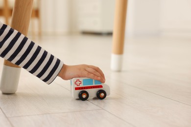 Little girl playing with toy car on floor at home, closeup. Space for text