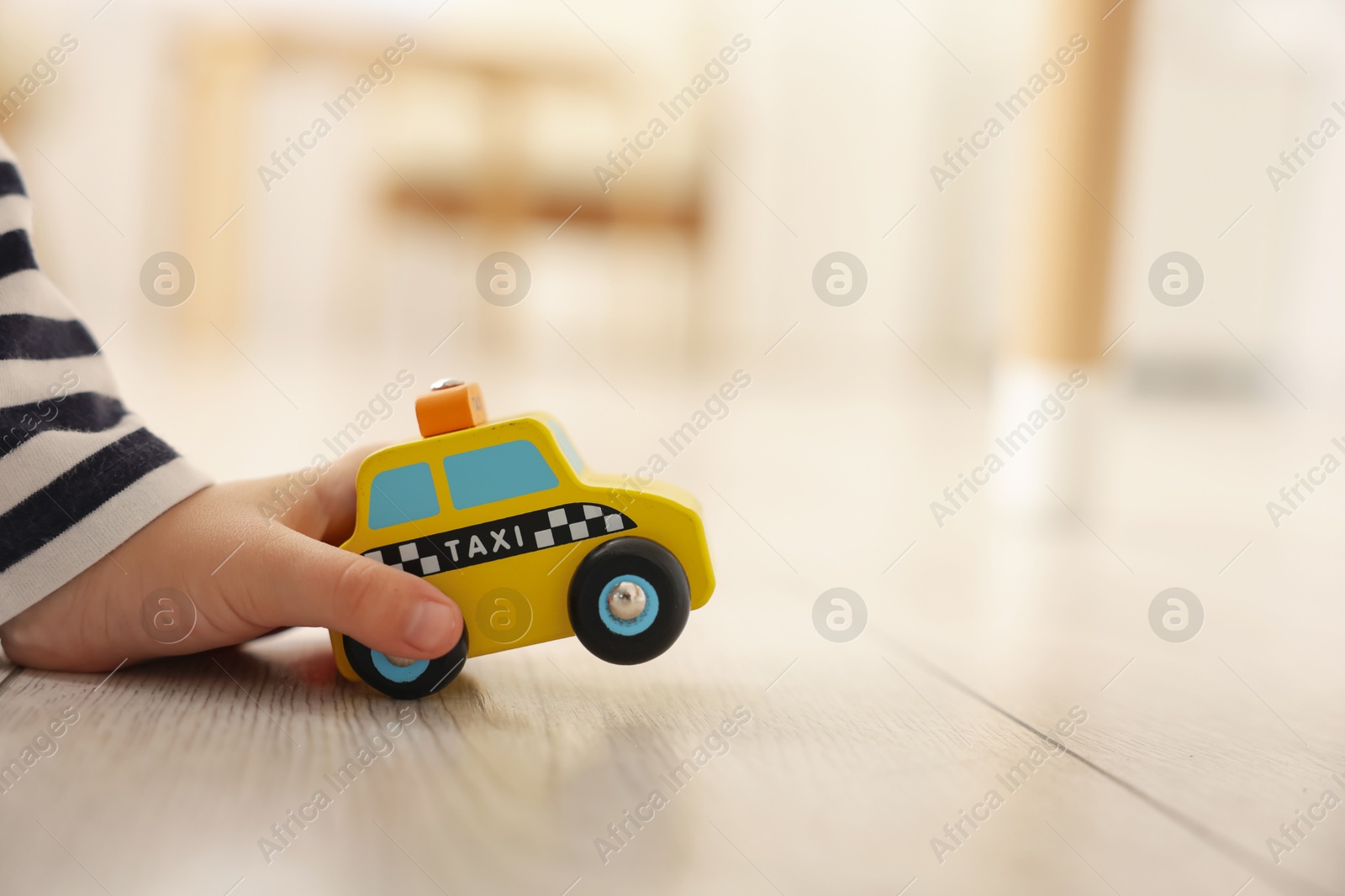 Photo of Little girl playing with toy car on floor at home, closeup. Space for text