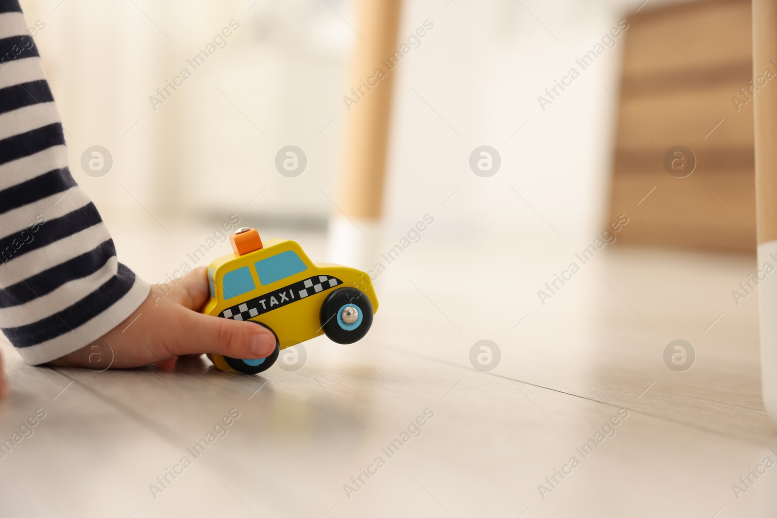 Photo of Little girl playing with toy car on floor at home, closeup. Space for text