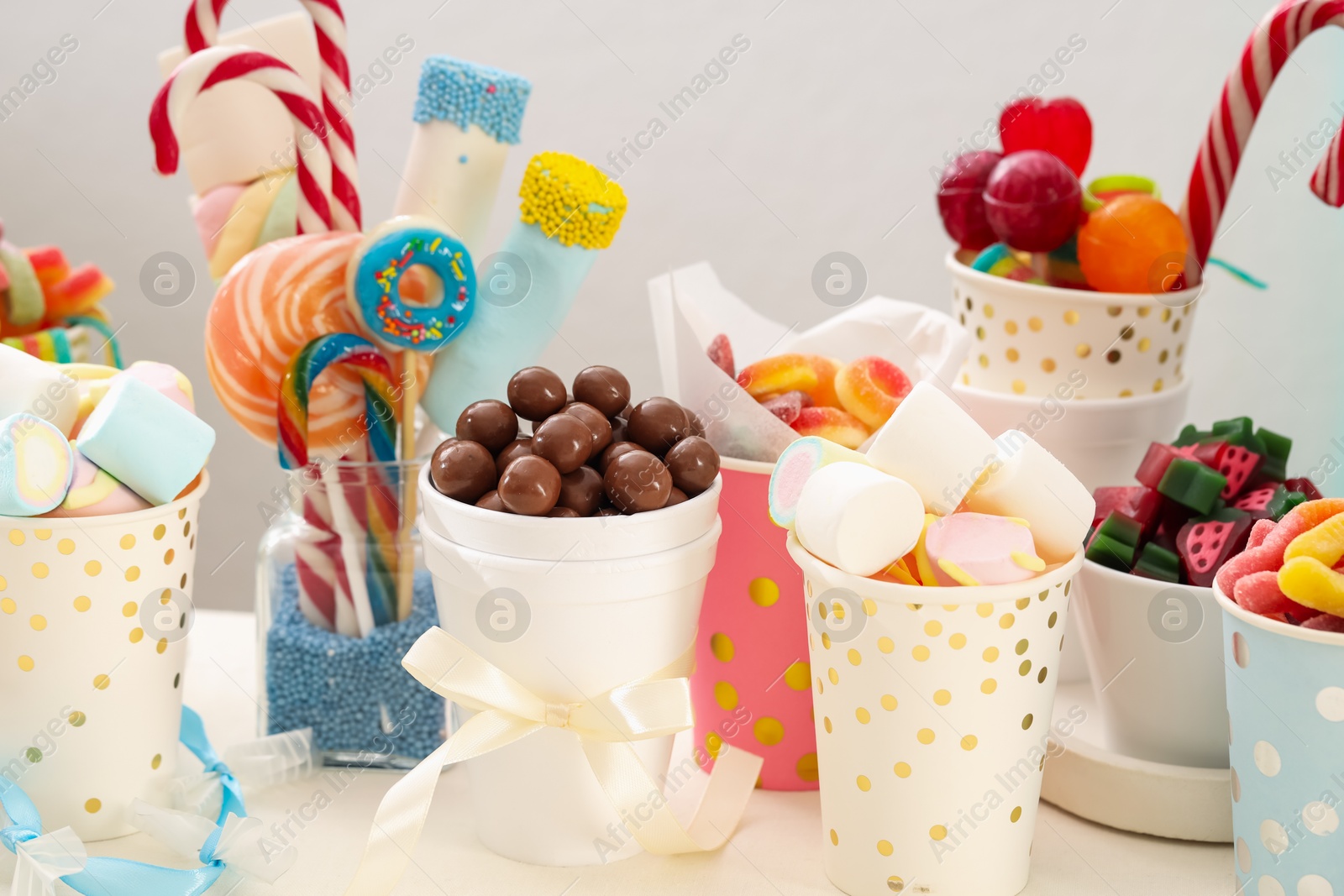 Photo of Candy bar. Different yummy sweets on white table against grey background