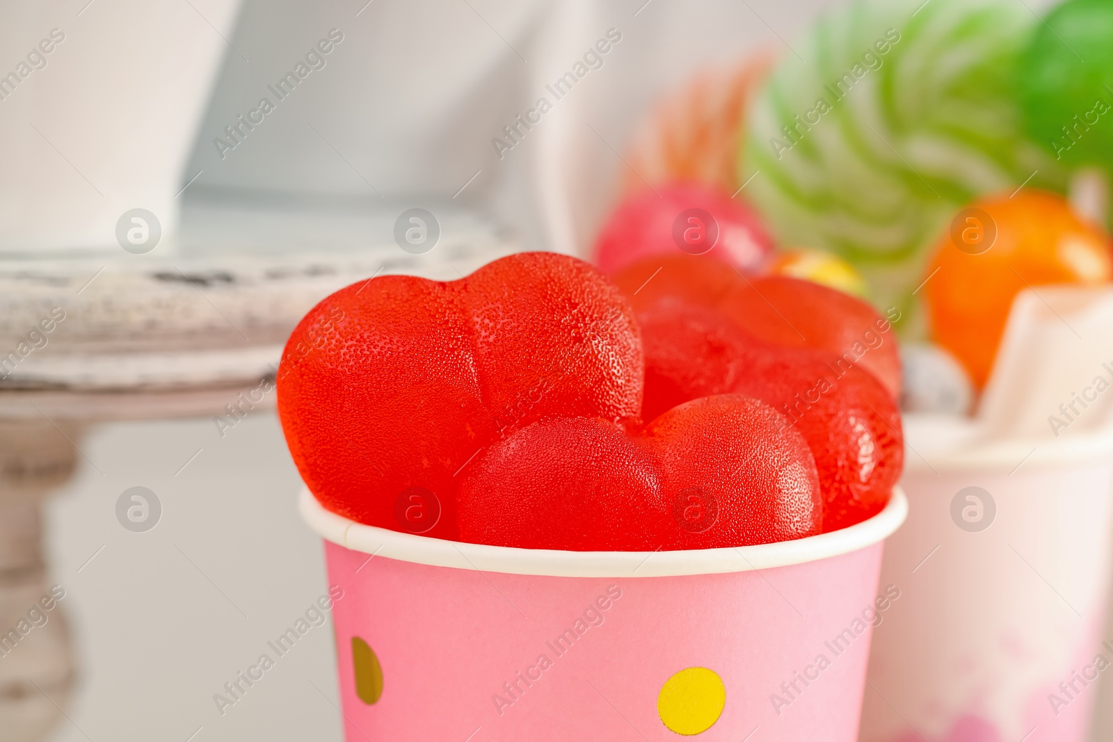 Photo of Candy bar. Yummy jelly sweets in paper cup on blurred background, closeup