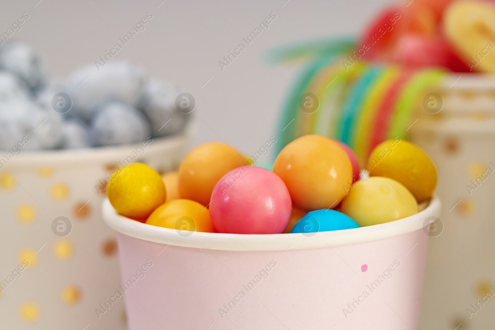 Photo of Candy bar. Colorful sweets in paper cup on blurred background, closeup