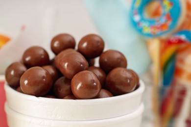 Photo of Candy bar. Chocolate sweets in paper cup on blurred background, closeup