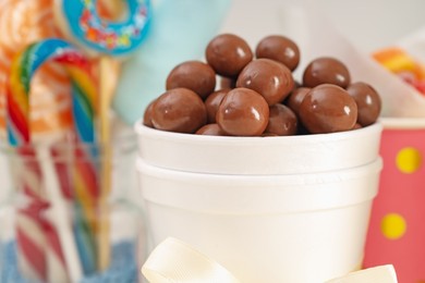 Photo of Candy bar. Chocolate sweets in paper cup on blurred background, closeup