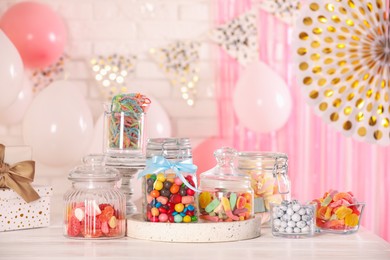 Photo of Candy bar. Many different sweets and gift boxes on white wooden table in festive decorated room