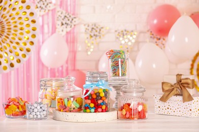 Candy bar. Many different sweets and gift boxes on white wooden table in festive decorated room