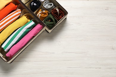 Organizers with folded clothes on wooden table, flat lay. Space for text