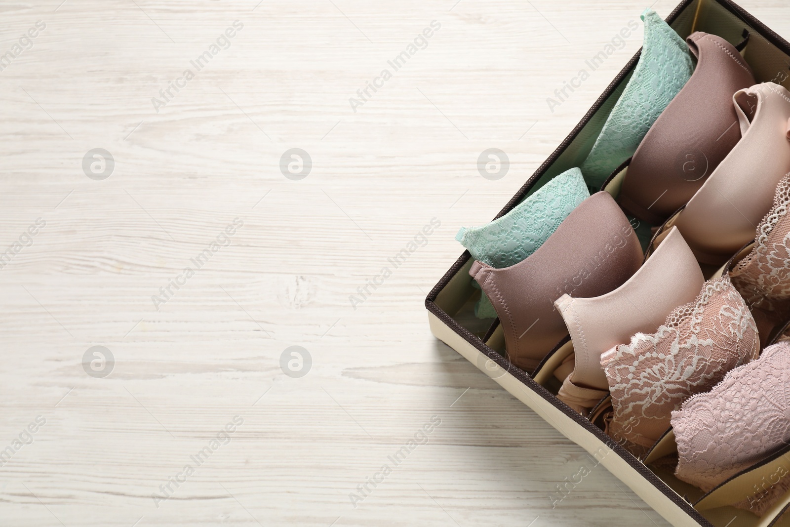 Photo of Organizer with bras on wooden table, top view. Space for text