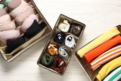 Photo of Organizers with folded clothes and underwear on wooden table, flat lay