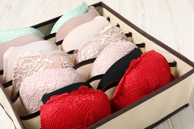 Organizer with bras on wooden table, closeup