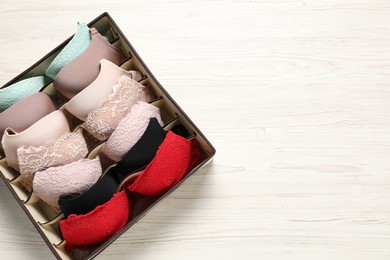 Organizer with bras on wooden table, top view. Space for text