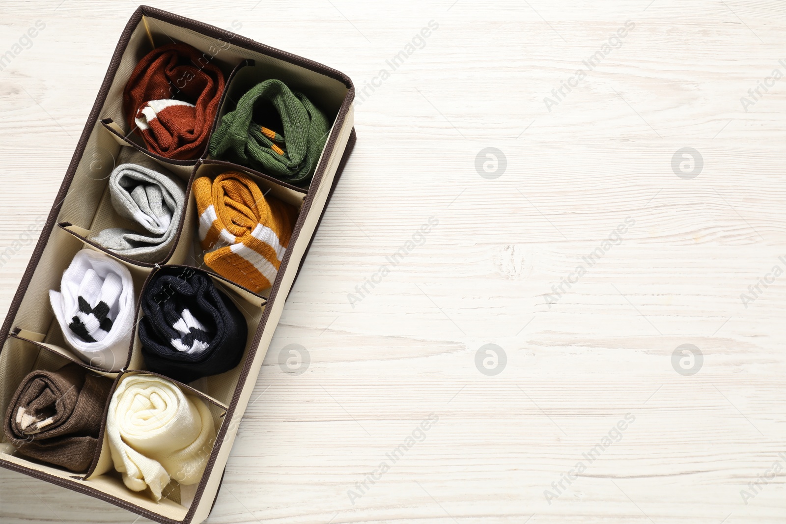 Photo of Organizer with different socks on wooden table, top view. Space for text