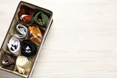 Photo of Organizer with different socks on wooden table, top view. Space for text