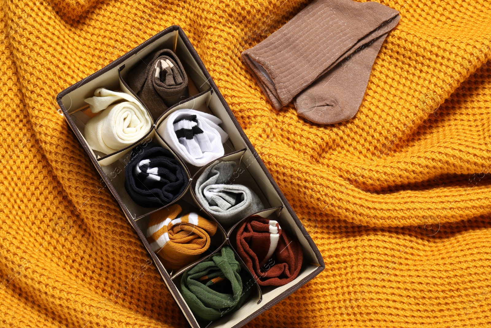 Photo of Organizer with different socks on orange blanket, flat lay. Space for text