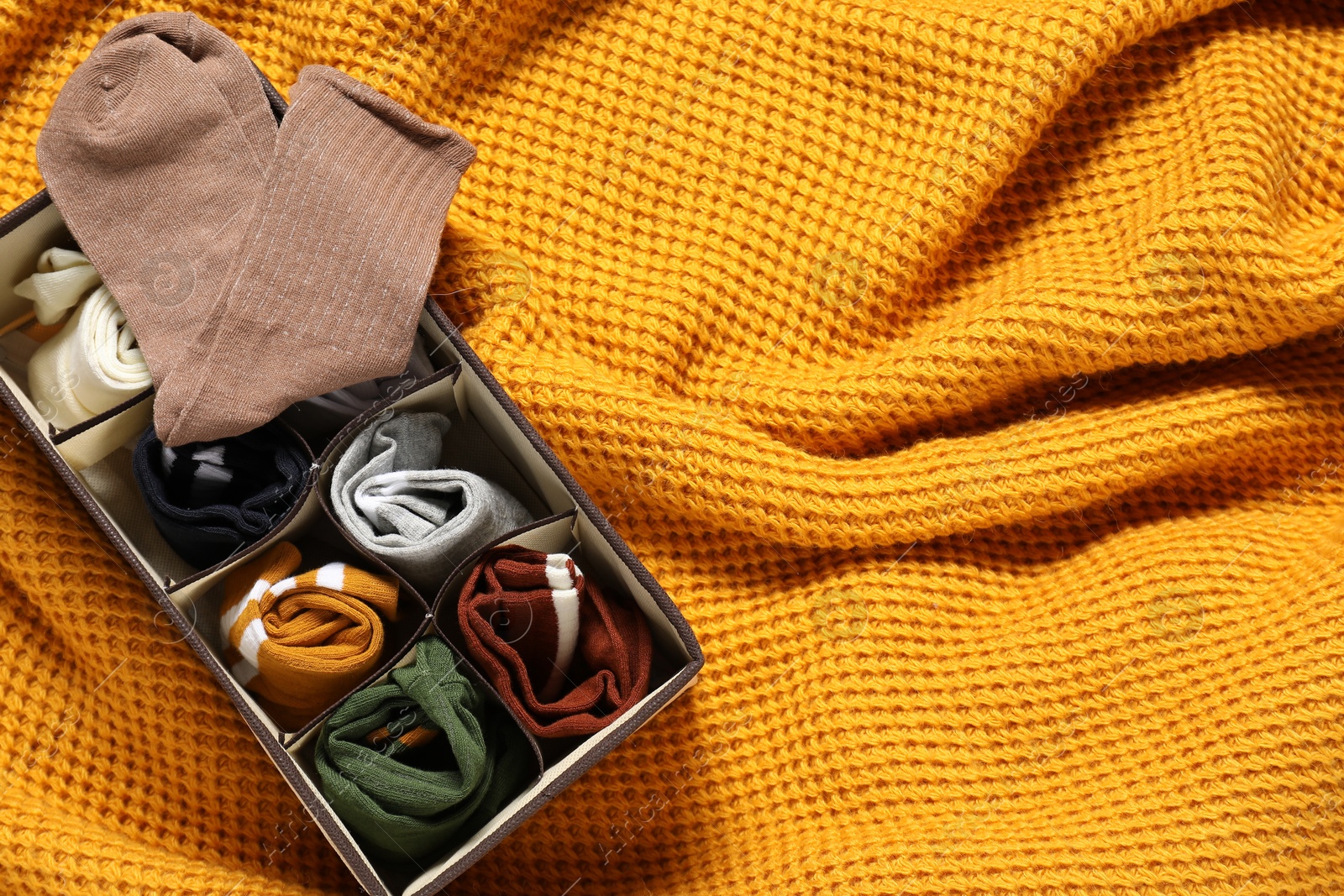 Photo of Organizer with different socks on orange blanket, top view. Space for text