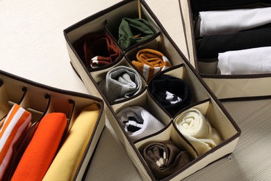 Organizers with folded clothes on light wooden table, above view